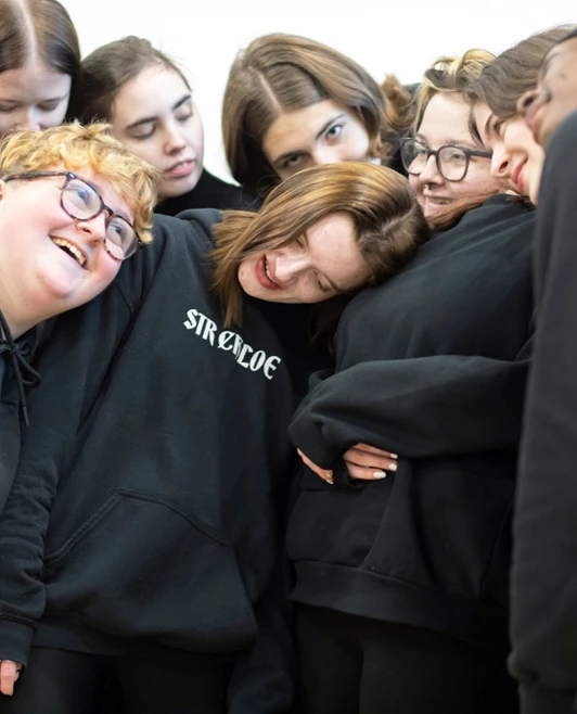 A joyful group of students huddling together, sharing laughter and support during a bonding exercise in the studio. A joyful group of students huddling together, sharing laughter and support during a bonding exercise in the studio.